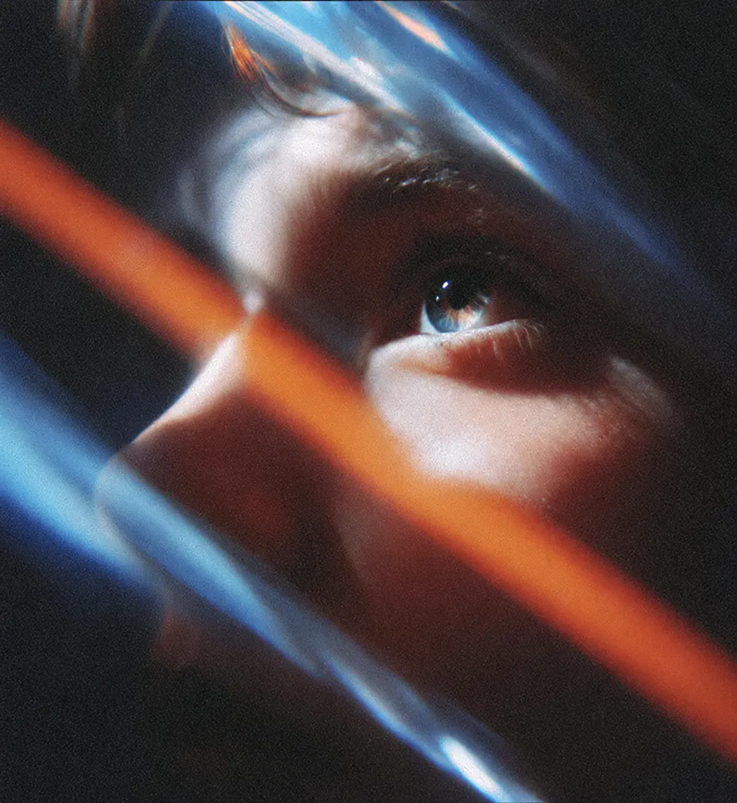 Close-up of an eye crossed by streaks of orange and blue light